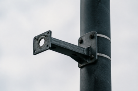 An empty camera mounting bracket on a street pole where a surveillance camera was removed