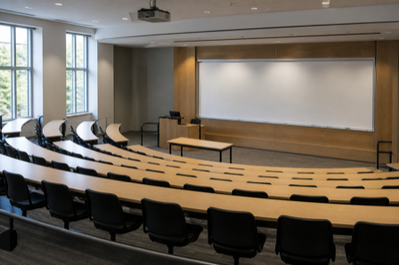 An empty university lecture hall with tiered seating and a blank whiteboard