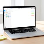 A laptop on a desk showing an organized notes app with a folder sidebar and colored tags, beside sticky notes