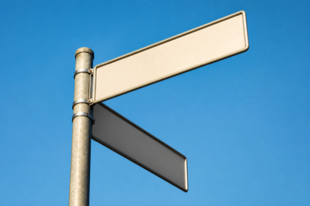 Blank street signs on a pole against a bright blue sky