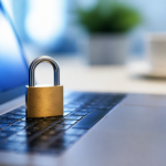A small brass padlock resting on a laptop keyboard lit by the screen's glow