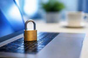 A small brass padlock resting on a laptop keyboard lit by the screen's glow