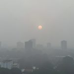 A Southeast Asian city skyline shrouded in thick grey haze at midday