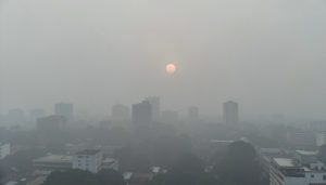 A Southeast Asian city skyline shrouded in thick grey haze at midday