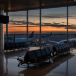 A quiet airport terminal at dusk with empty seating overlooking parked planes