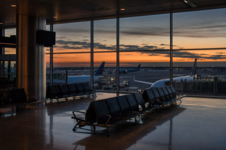 A quiet airport terminal at dusk with empty seating overlooking parked planes
