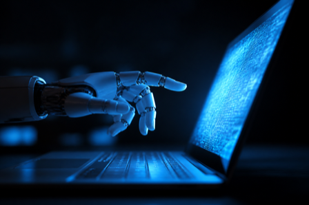 A robotic hand reaching toward a glowing laptop screen in blue light