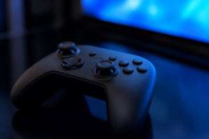A generic game controller on a dark reflective surface lit by a blue screen glow