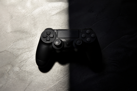 A game controller on a surface split between bright light and deep shadow