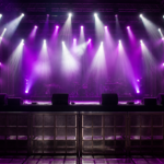A concert stage lit with purple and white spotlights and atmospheric haze