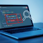 A laptop showing code with one block outlined in red and a magnifying glass over it, representing a schema audit